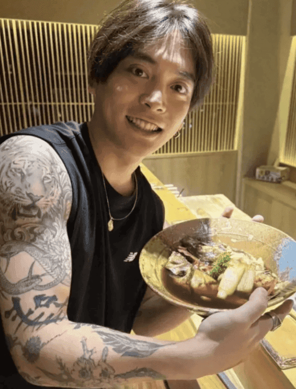 寿司店で料理の皿を持つ優里さん。黒いタンクトップから出た右腕に、肩から手首までタトゥーが入っている
